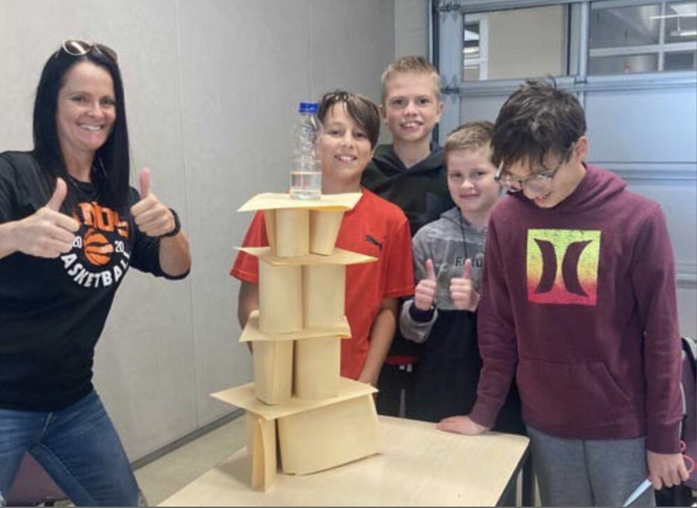 students with homemade tower and teacher beside them with thumbs up