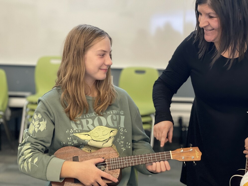 student playing mandolin with teacher helping