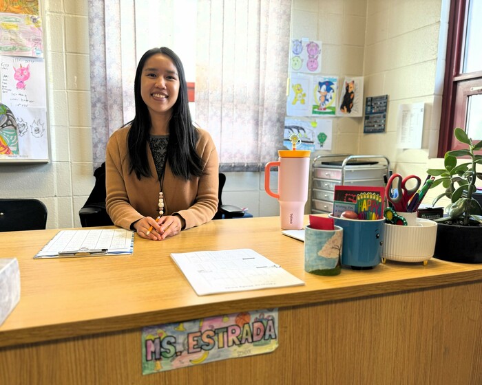 Ailee Estrada sits behind her desk smiling.