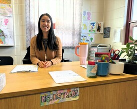 Ailee Estrada sits behind her desk smiling.