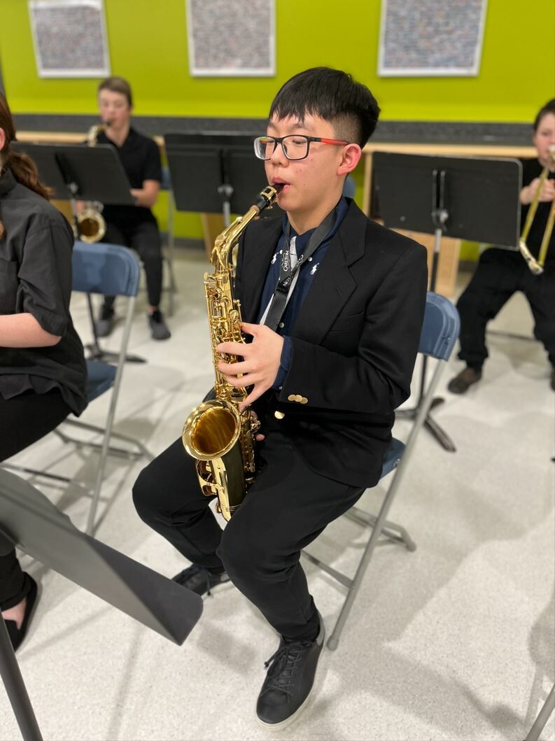 student sitting and playing saxophone