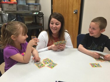 teacher working with 2 students with cards